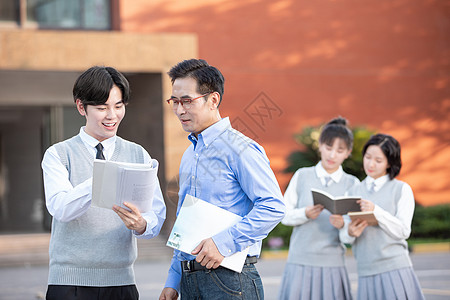 校园里学生和老师讨论课本知识背景图片