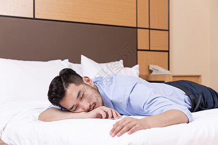 商务男性酒店出差趴在床上睡觉图片