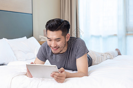 商务男性躺在酒店床上看手机背景图片
