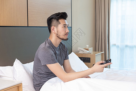 躺在床上看电视男性躺在酒店床上看电视背景