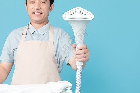 使用挂烫机熨烫衣服的家政服务男性特写图片