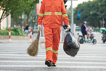 拎着垃圾袋与扫帚的环卫工人过马路图片