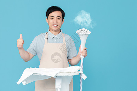 男性清洁人员使用挂烫机熨烫衣服的家政服务男性背景