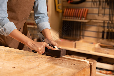 工匠用刨子削木头特写图片