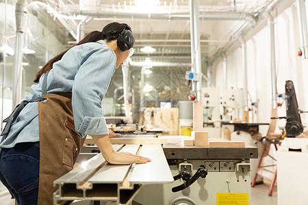 女性工匠用切割机锯木头背影图片素材