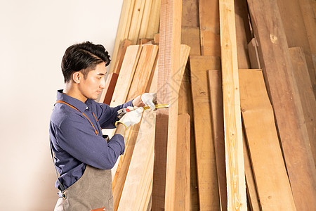 男性木工挑选测量木材物料图片