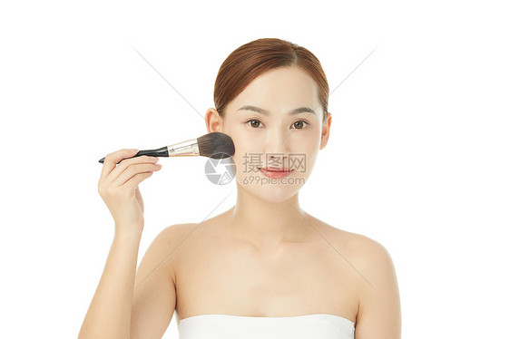 女性使用化妆刷刷脸颊图片
