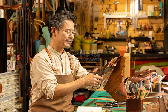 中年男性皮匠裁剪皮料图片