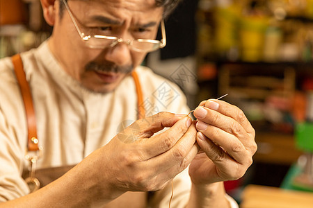 中年男性皮匠穿针引线图片