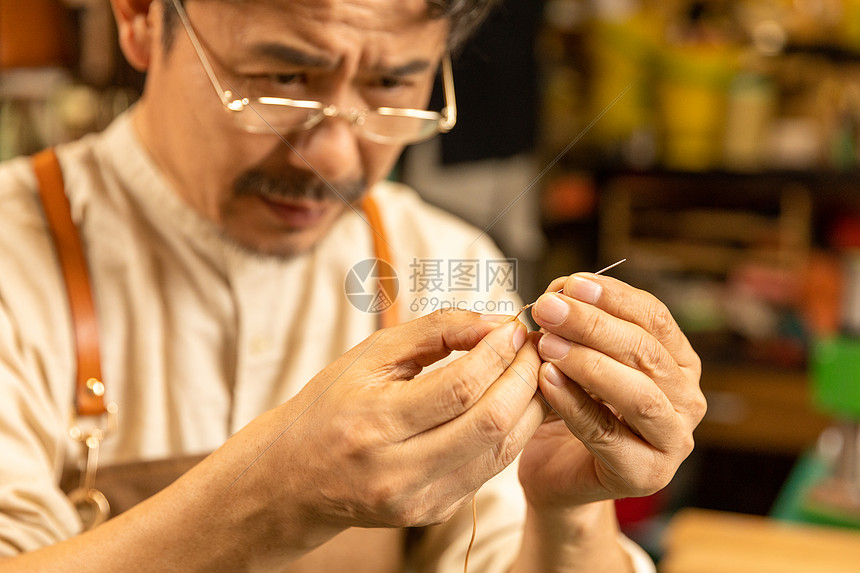 中年男性皮匠穿针引线图片