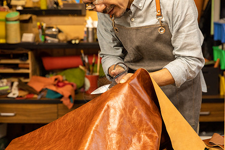 中年男性皮匠切割剪裁皮料图片