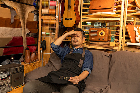 中年男性皮匠劳累在工作室休息图片