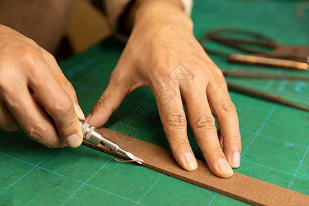 缝制皮具中年男性皮匠手工缝制皮带细节背景