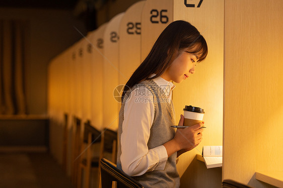 女大学生手捧咖啡杯自习室认真学习图片