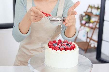 美女居家制作水果蛋糕撒糖粉高清图片
