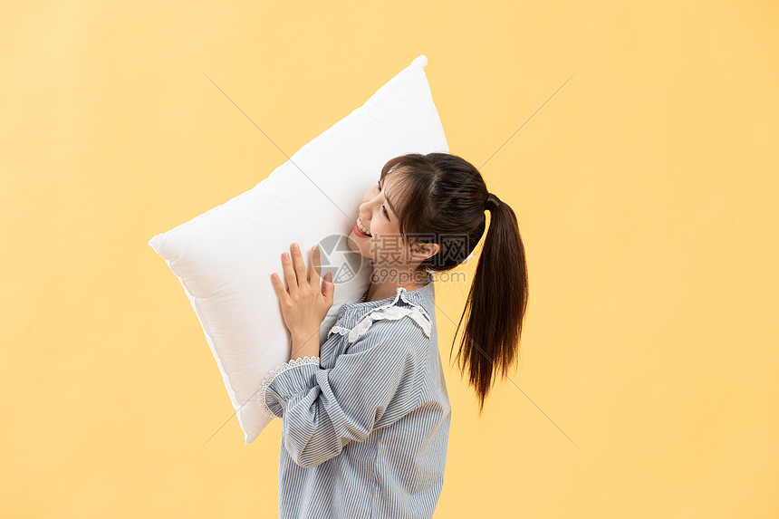 穿着睡衣的女孩手抱枕头图片