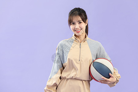紫色服装穿休闲服的甜美女性与篮球背景