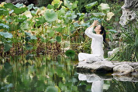 瑜伽垫河边做瑜伽修身养性的女性背景