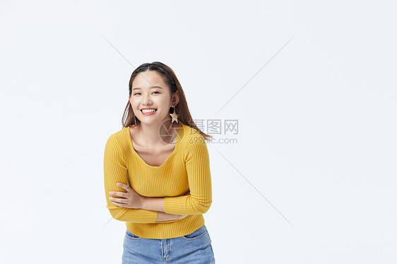 穿黄色毛衣双手环抱弯腰自信微笑的长发美女图片