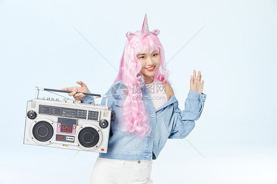 单手提着录音机挥手的时尚粉色长发美女图片
