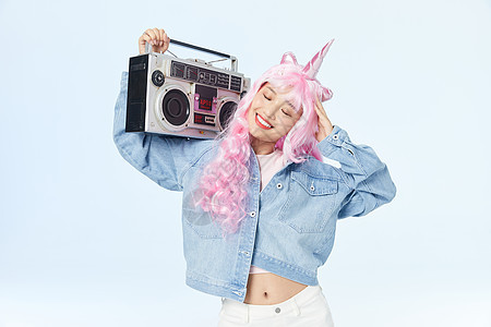 录音机放在肩膀上享受音乐的时尚粉色长发美女图片