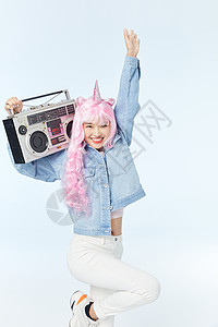 录音机放在肩膀上单脚站立的时尚粉色长发美女图片