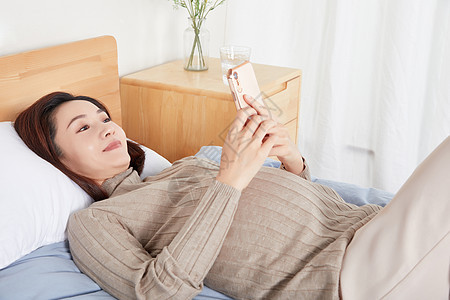 孕妇在床上开心的玩手机图片
