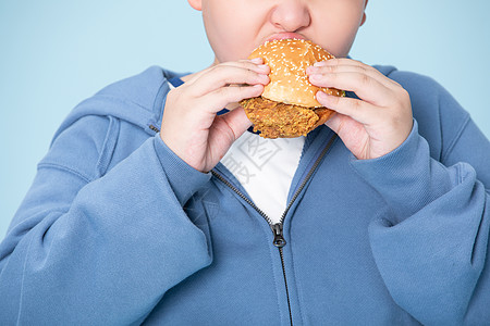 高热量食物小男孩大口吃汉堡肥胖的男孩特写背景