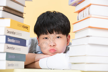 在复习的男孩为学习发愁的小男孩在书前发呆背景