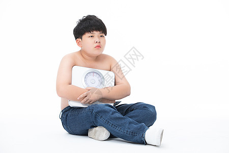 男孩抱着体重秤心情失落肥胖图片