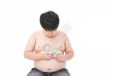 生病的小男孩小胖子低头看药图片