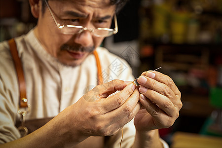 中年男性皮匠穿针引线高清图片