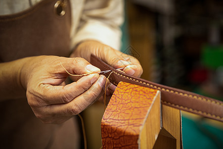 男性工匠手工制作皮带特写背景图片