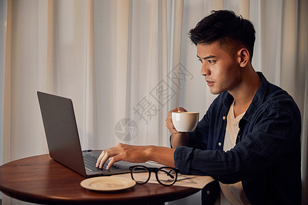 年轻男士晚上在家喝咖啡加班图片