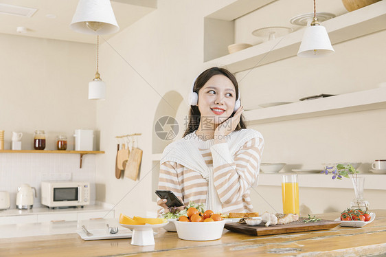 头戴耳机听音乐的女孩享受午餐图片