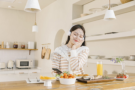 头戴耳机听音乐的女孩享受午餐图片