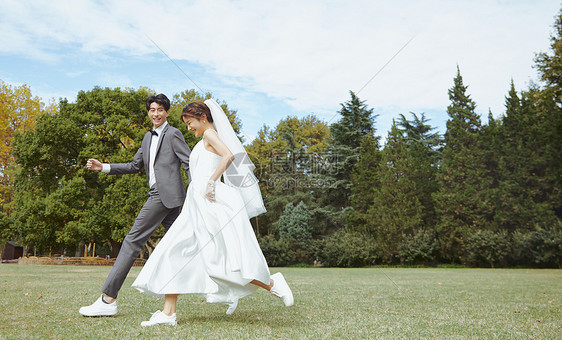 在草坪上牵手奔跑的情侣图片