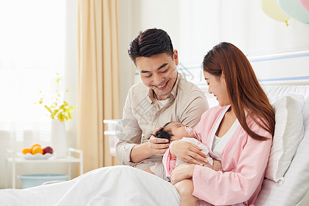 年轻爸爸和妈妈在病床上照顾婴儿宝宝高清图片