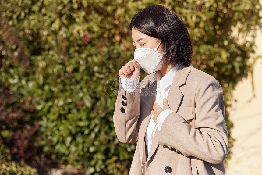 户外带着口罩咳嗽的女性图片