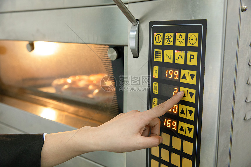 烘焙师使用烤箱烘烤面包特写图片