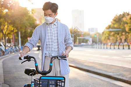 佩戴口罩的男性为共享单车消毒图片