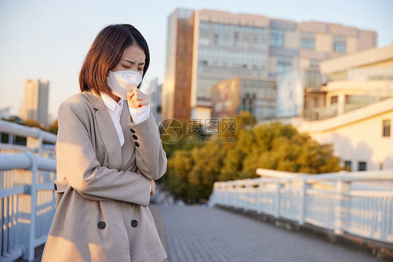 户外佩戴口罩咳嗽的青年女性图片