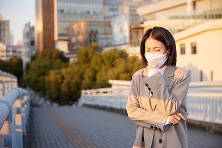 户外佩戴口罩咳嗽的青年女性图片