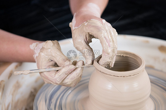 陶艺匠人手工制作切割陶艺品特写图片