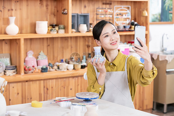 美女拿手机拍摄陶艺半成品图片