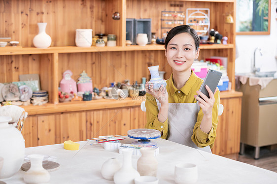 美女拿手机拍摄陶艺半成品图片