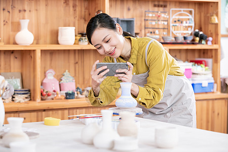 美女拿手机拍摄陶艺半成品图片