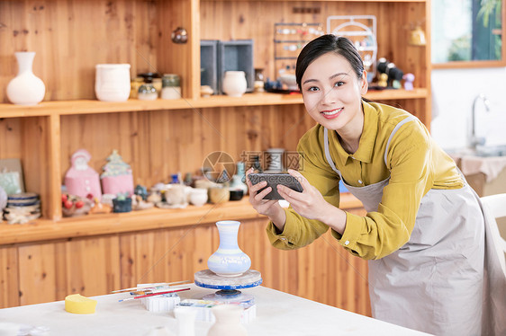 美女拿手机拍摄陶艺半成品图片