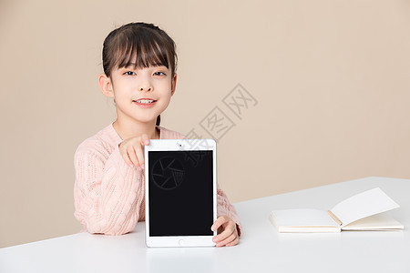 女孩在课桌上手拿着平板电脑背景图片