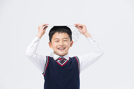 小学生校服小男孩头顶平板电脑背景